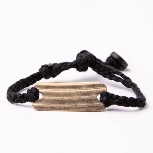 Black braided bracelet with a bronze rectangular tag on a white background